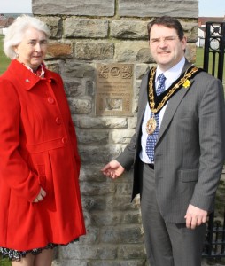 Caerphilly County Borough Council's Mayor, Cllr James Fussell and Mrs Christine Phillips with the bronze plaque on the town's Eisteddfod Gates.