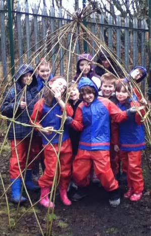 Some of the children from Ysgol Gynradd Gymraeg Penalltau check out their willow “hobbit home” for size