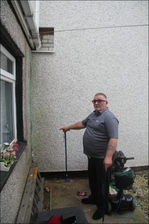 DAMAGE: Mr Jones points to where guttering pipe was pulled from the brick wall to allow for the white cladding to be fitted next door