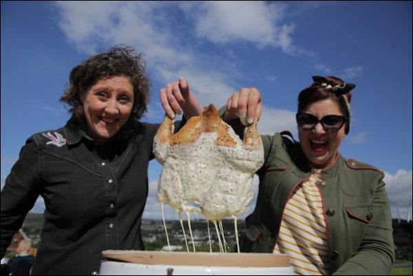 Barbecue experts and restaurateurs Samantha Evans and Shauna Guinn holding up a chicken ready for barbequing