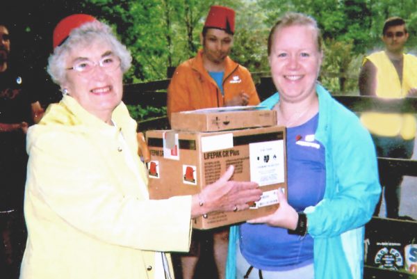 Margaret Jones, of the Tommy Cooper Society, left, presents a defibrillator to Anouska Beaumont, Event Director of Penallta Park Run