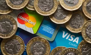 Mastercard, American Express and Visa credit cards with UK one pound coins.
