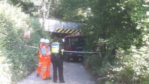 A skip lorry stuck under the Tynygraig railway footbridge