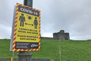 A social distancing warning sign near Caerphilly Castle