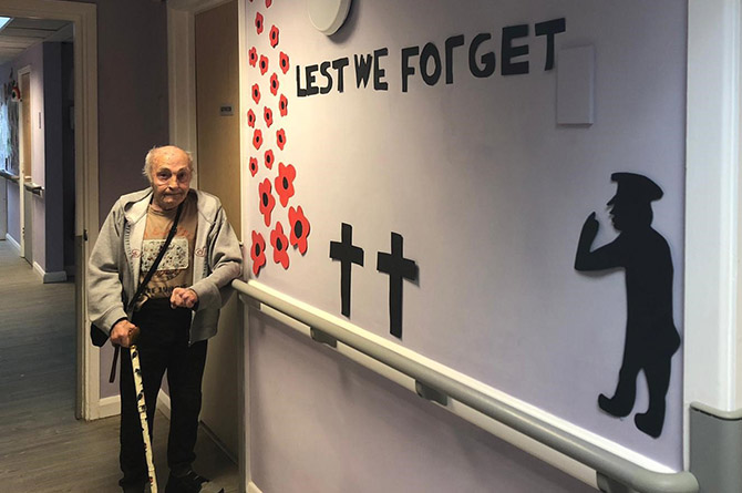 Ty Clyd resident Gaz standing next to a Remembrance mural