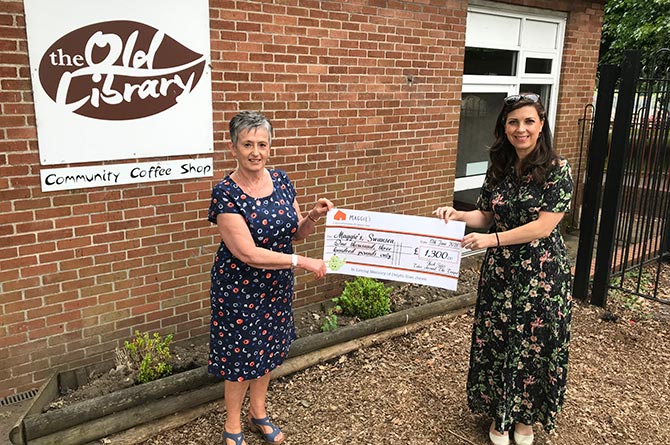 Rhianwen Mills, left, presents a cheque worth £1,300 to Lucia Osmond of Maggie's cancer centre, at the Old Library Cafe