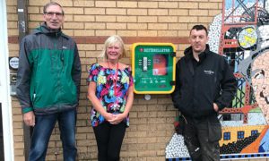 Cllr Walter Williams, left, with community centre manager Sharon Burrell and electrician Matthew Taylour next to the newly-installed heart defibrillator in Markham