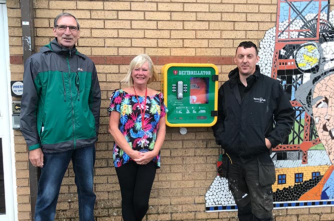 Cllr Walter Williams, left, with community centre manager Sharon Burrell and electrician Matthew Taylour next to the newly-installed heart defibrillator in Markham