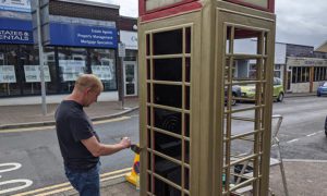Volunteer John Thomas painting the telephone box on Penallta Road in homage to Olympic gold-medallist Lauren Price