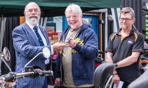 Norman Hyde, left, presents the ignition key to Simon Weston, centre, and Hank Hancock of Trike Design