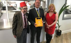 Catering tutor Stuart Davies, centre, is presented with a heart defibrillator by the Tommy Cooper Society's Tudor Jones MBE and Sharon Owen of Calon Hearts