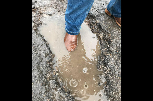A puddle formed in one of the potholes in the middle of the road entering the Kingsmead estate