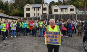 Leighton Reardon, grandfather of Laurie Jones, holds a placard reading: "Weak fence from a weak council"