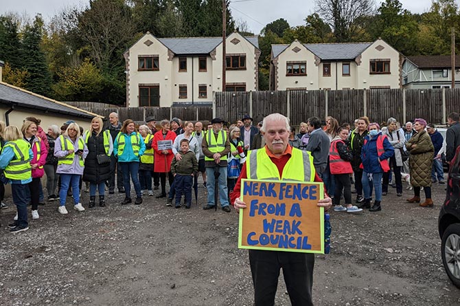 Leighton Reardon, grandfather of Laurie Jones, holds a placard reading: "Weak fence from a weak council"