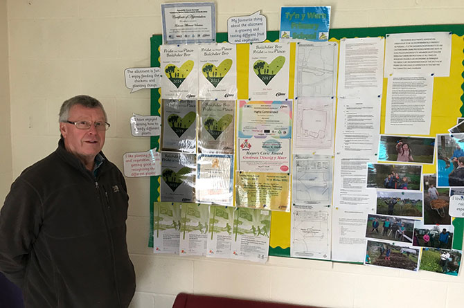 Billy Hughes standing next to the Trethomas Allotment Association's awards board