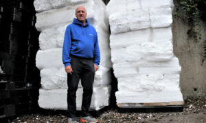 Graham Middleton standing in front of around a tonne of compacted polystyrene ready to be exported