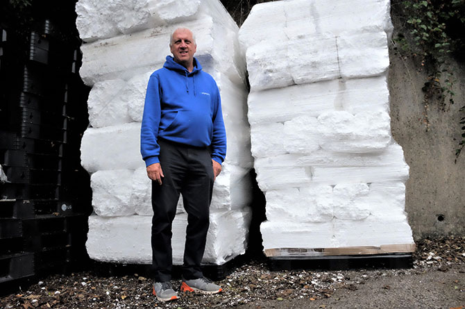 Graham Middleton standing in front of around a tonne of compacted polystyrene ready to be exported