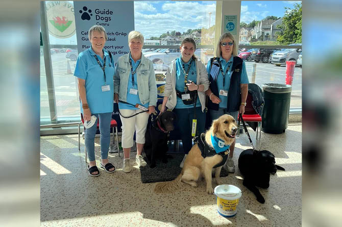 Guide Dogs Cymru volunteers holding a supermarket collection
