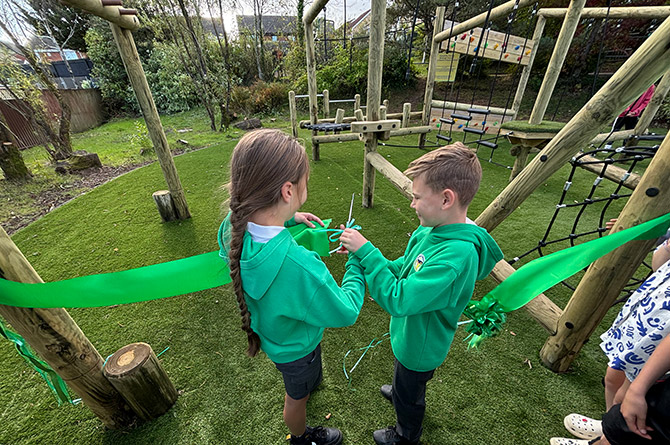 Cwrt Rawlin's head girl and head boy cutting the ribbon to officially open their new school playground