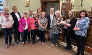 Members of Phoenix Ladies presenting a cheque to Caerphilly Miners' Centre's Sophie Davies and Karina Allaway