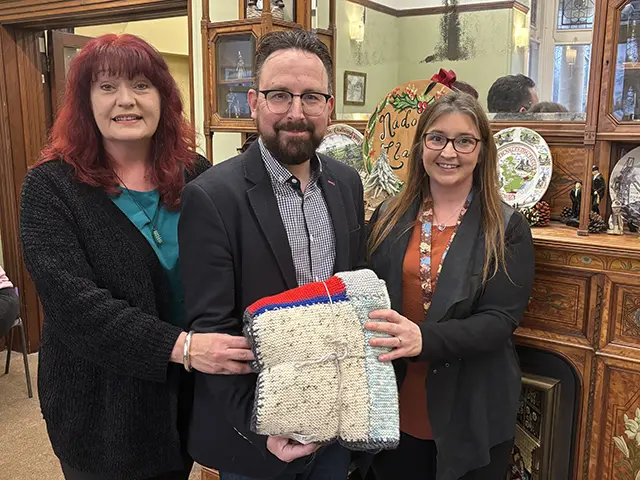 Hefin David MS presenting blankets to Llamau's Lisa Carlsen, left, and Zara Stainer