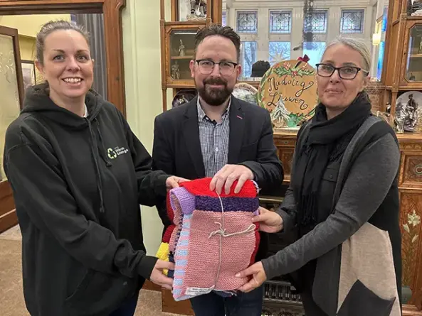 Hefin David MS presenting a blanket to Lisa Watkins from Caerphilly Uniform Exchange, left, and Michelle Moore of Van Community Council, right