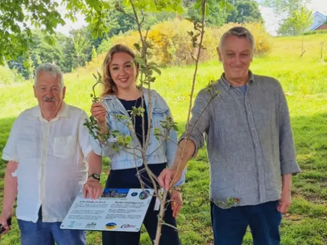 Yuliia Bond, centre, and Wales Green Party leader Anthony Slaughter, right, planting the apple tree at Morgan Jones Park