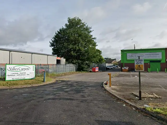 Valley Carpets, in Port Road, with application site behind building on left, pictured in June 2025