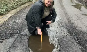 Mair Arthur, the landlady of the White Cross Inn, measuring the depth of a pothole in Groeswen Lane